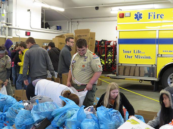 Senior, Stephen Naylor pictured left side, boxes canned foods as they come into the firehouse on the morning of Scouting for Food.