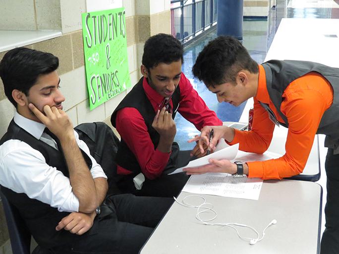 Sid Rana, senior, Akash Sarkar, sophomore, and Rahul Ravichandran, sophomore, manage room assignments for the Saturday debates. They worked with other students to keep the tournament on schedule. 