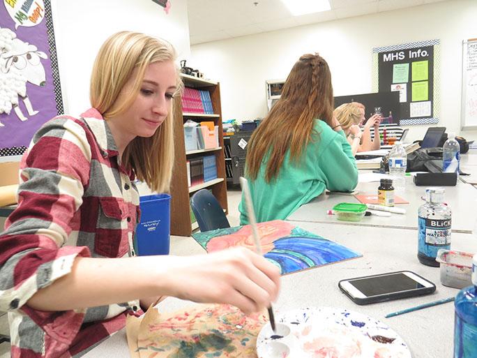 Kate Hollander, senior, adds the finishing touches to a watercolor piece. 
