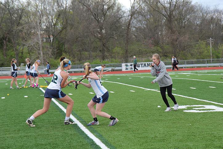 Claire Green, senior, helps run a drill for Erin Underwood, senior, and Caroline Tunis, junior, before their game against Rockwood Summit on April 6. They won 14-2. 