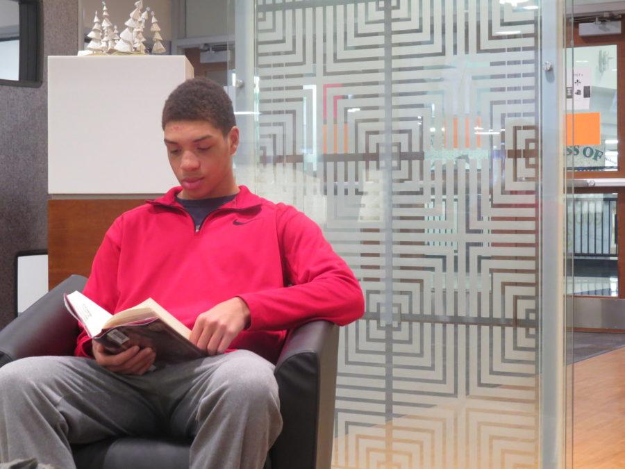 Israel Williams, senior, sits down in the library to read a book for the annual Marquette Reading Marathon. Williams is one of 70 students and faculty to participate in the event.