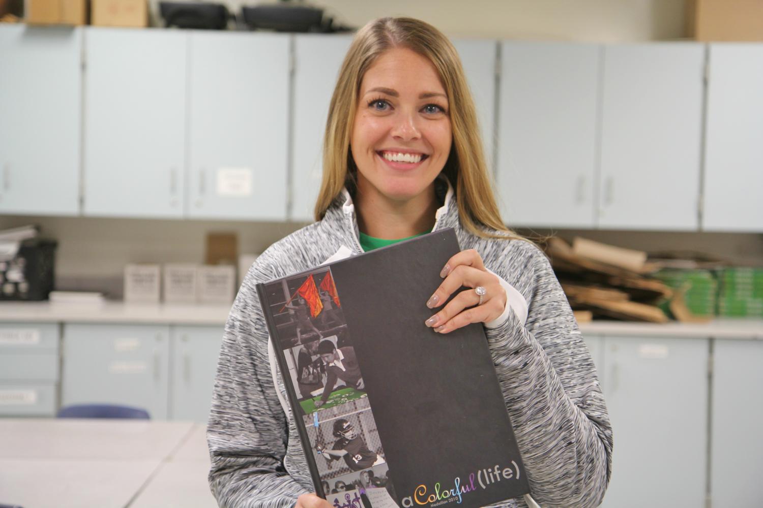 Kenzie McKeon, art teacher, poses with the 2010 MHS Yearbook. McKeon was voted Most Likely to Work at MHS.