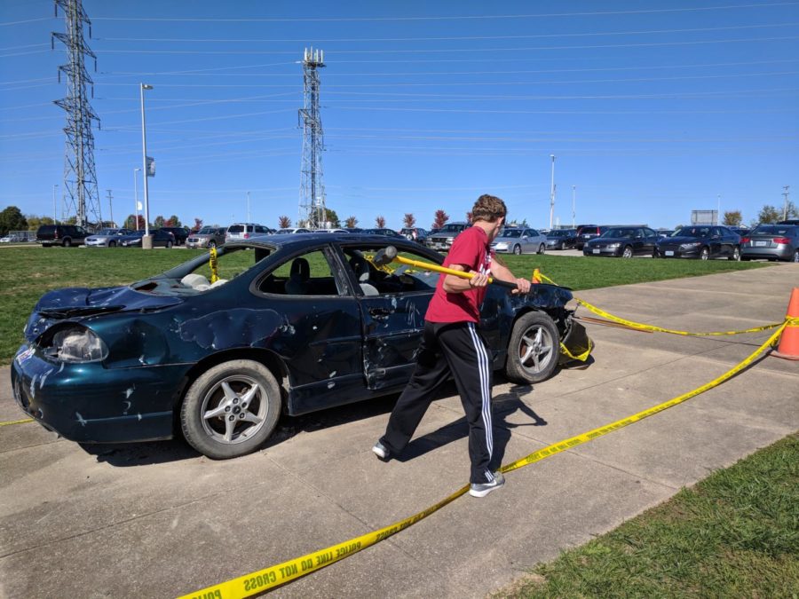 Jackson Estwanick, sophomore, takes a hammer to a decommissioned car for SADDs annual car bash. Estwanick and other students paid one dollar each to take a swing at the car.