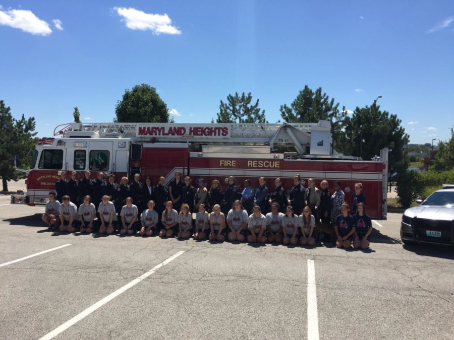 Campers, counselors, and first responders line up in front of a fire truck at the 2017 Camp Fury STL graduation.
