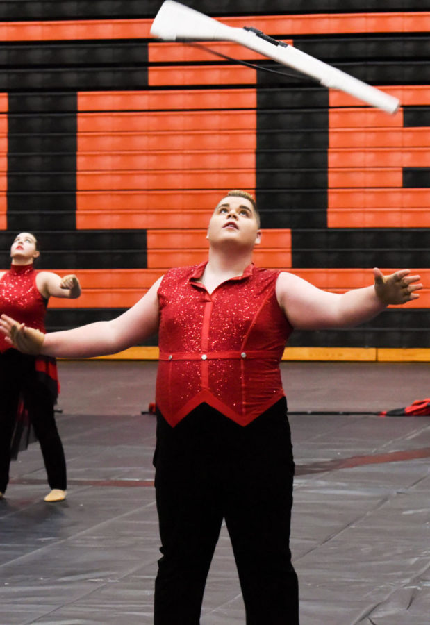 Will Phillips, junior, tosses the rifle in the air while performing at the Scholastic AA at Edwardsville High School Winter Guard competition on Feb 2. Winter guard took first in their division at the competition.
