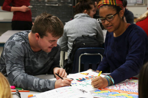 Austin Combs, senior, laughs with his mentor Mary Olubogun, junior, as he draws on his folder during Art Fundamentals. 
