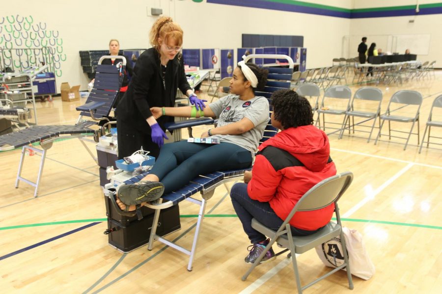 Mary Olubogun, senior, speaks with Amy Walters, Mississippi Valley Regional Blood Center volunteer, while she bandages her arm with Adria Martin, sophomore, alongside her. Olubogun said she liked the addition of the free t-shirt and later reflected on her motivation to donate these past years. “There are people that need blood, and it’s cool, even if it’s a little tiny bit, to help them out,” Olubogun said. “I like that we keep getting the opportunity to help the community as a school is really cool and interesting.”