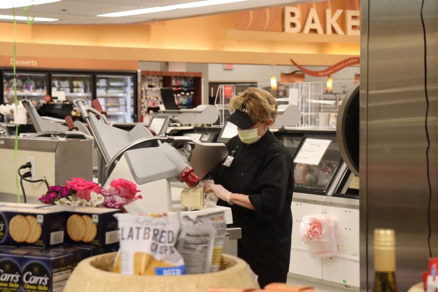 Schnucks employee slices meat wearing a mask and gloves.