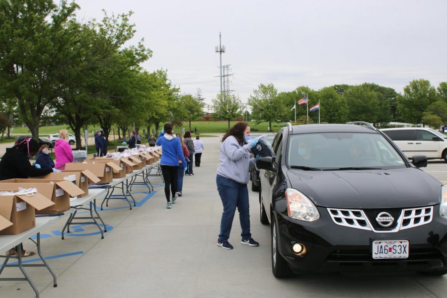 Caps and gown packages are delivered to senior’s car windows by MHS staff members wearing masks and gloves.