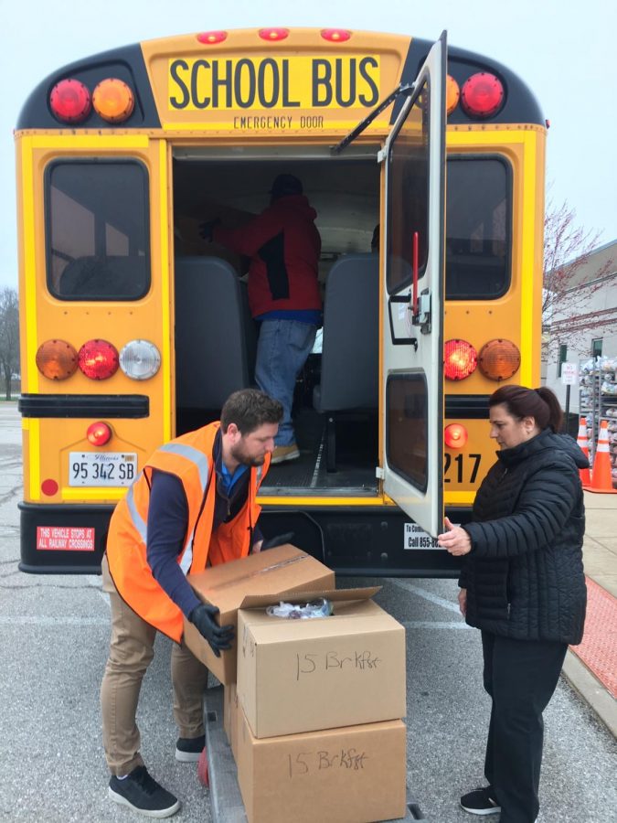 South Base Terminal Manager Alex Gensler (left) and Starr Giammanco, meal distributor, (right) load school buses with boxes of prepared meals for regional distribution. 