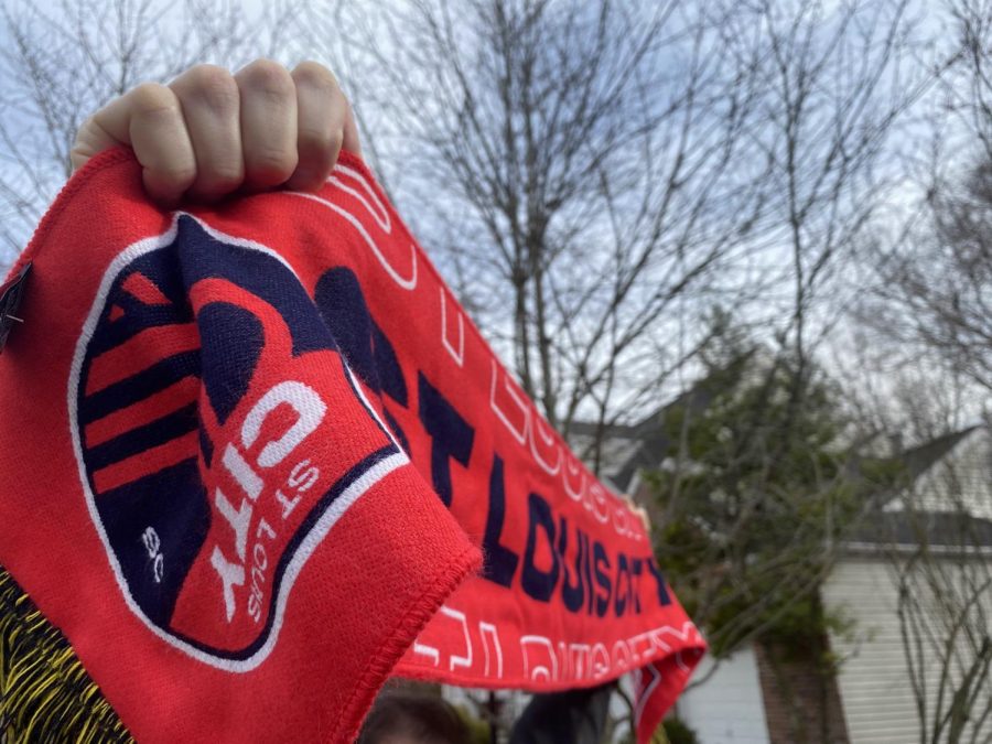A St. Louis City scarf is raised showcasing the new emblem and colors of the team. The franchise has begun selling apparel which is now available on the STL City fan shop online.