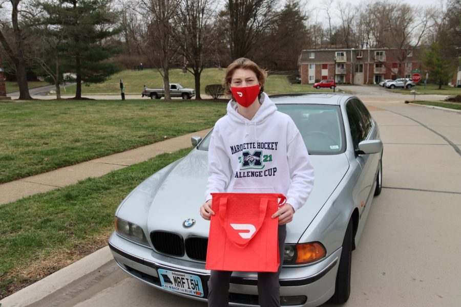Larson Hill, senior poses with his car, warming bag and mask, all required for his job delivering food for DoorDash. Recently, DoorDash has become a popular employer for MHS students due to it’s easy sign up, flexibility and high pay.  
