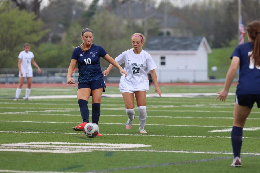 Junior Taryn Moore, attacking midfielder, lays off a pass to a teammate as a St. Josephs player pressures.