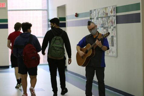 Edward Bolton, science teacher, strums his guitar during the passing period before module two of Academic Lab. Bolton said he is currently in the learning phase as a guitarist, but he hopes to be able to master the craft with more practice and venture beyond his current range of songs. 