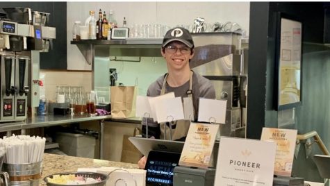 Mark Kohler, Class of 2018, smiles while standing at the cash register at Pioneer Bakery Cafe. Kohler is now the face of the Smiley Face Cookie Company and works to decorate the cookies. 