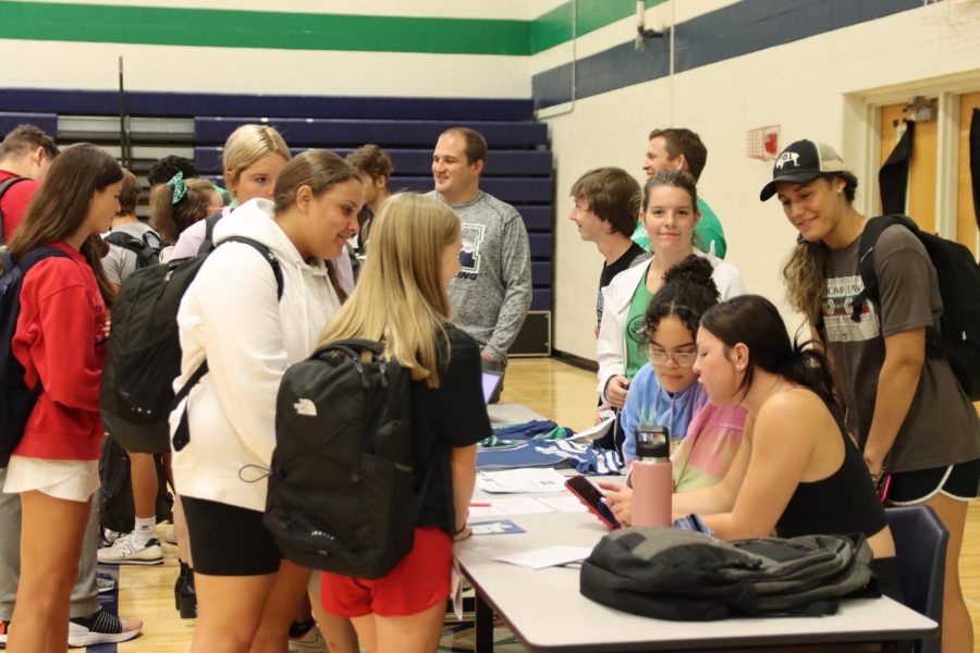 Freshmen Lexi Morgan and Ellie Pagan learn about the wrestling team in the gym during the Activities Fair Aug. 31. There were a total of 85 booths spread throughout the hallways, the Commons and the gym. Most of them were set up and run by the students in the clubs.