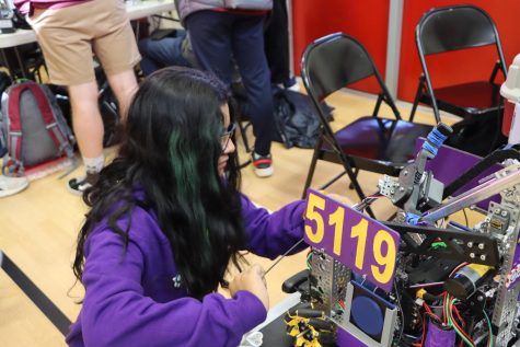 Sanjana Chirra, senior, tweaks the Baryons’ robot’s claw system. In order to score points, each robot must be able to have a functional claw to pick cones up. “The servos seemed to have an issue so we were troubleshooting it to see any problems so we had loosened the servo holders,” Chirra said.