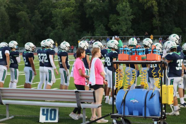 Seniors Kayla Gifford and Makayla Cook stand on the sidelines at MHS first home football game ready to assist the players with water. We basically just help the players and team out so the coaches can worry about the game, Gifford said. 