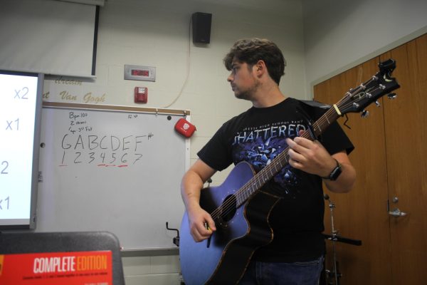 Sean Schierbecker, guitar teacher, models basic chords during a lesson to his fourth-hour students. Schierbecker is self-taught on the guitar. 