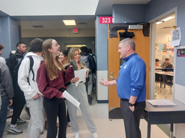 Kevin Schultz, language arts teacher, talks with several students during the first-ever academic fair. The fair took place during Mod 2 of Ac Lab on Thursday, Jan. 18, and allowed students to travel throughout the building to ask teachers about classes. 