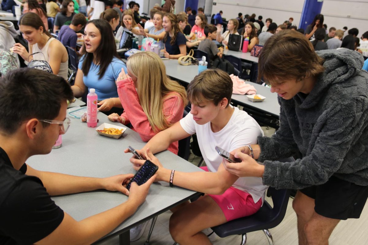 Tristan Chambliss and Will Kozeny, juniors, along with Corbin Garrett, sophomore, use their phones during lunch. Since lunch falls within the Tech Green Zone, technology use is permitted.