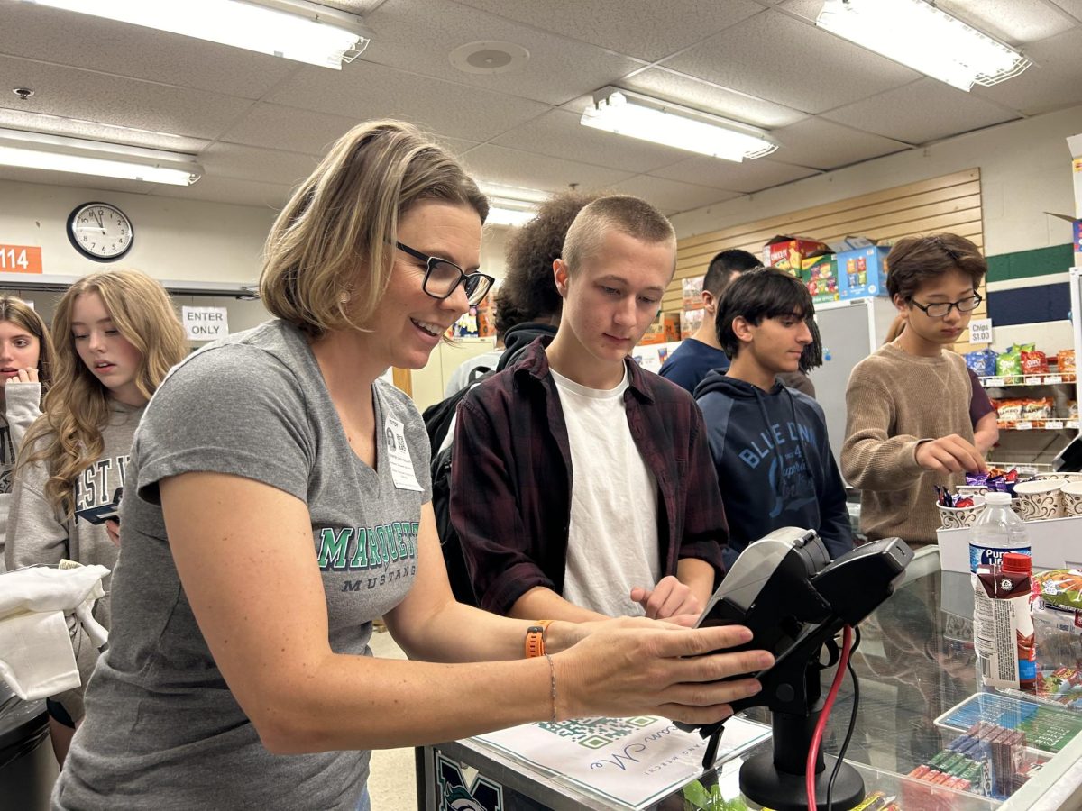 Jennifer Leigh Gillian, MPO volunteer, helps Jackson Warden, senior, with completing his credit card transaction for purchasing food from the school store. When using a credit card for payment, students are required to spend a minimum of $5. Gillian is one of many parents who volunteers in the school store.