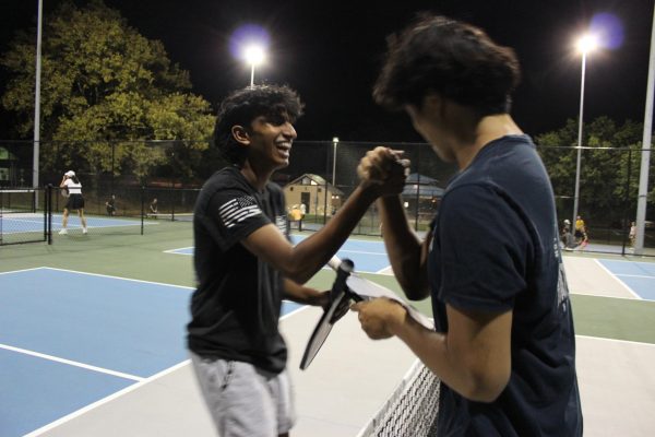 Aash Pammi, junior, and Henry Chen, senior, shake hands after a pickleball match, demonstrating sportsmanship.