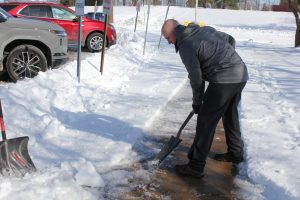 Junior Principal Kyle Devine scrapes snow off the sidewalks to ensure student safety. "We were able to get rid of a decent amount of the snow, but then obviously the hard kind of compacted ice is a safety issue, so we're just breaking it up before the end of the day,” Devine said