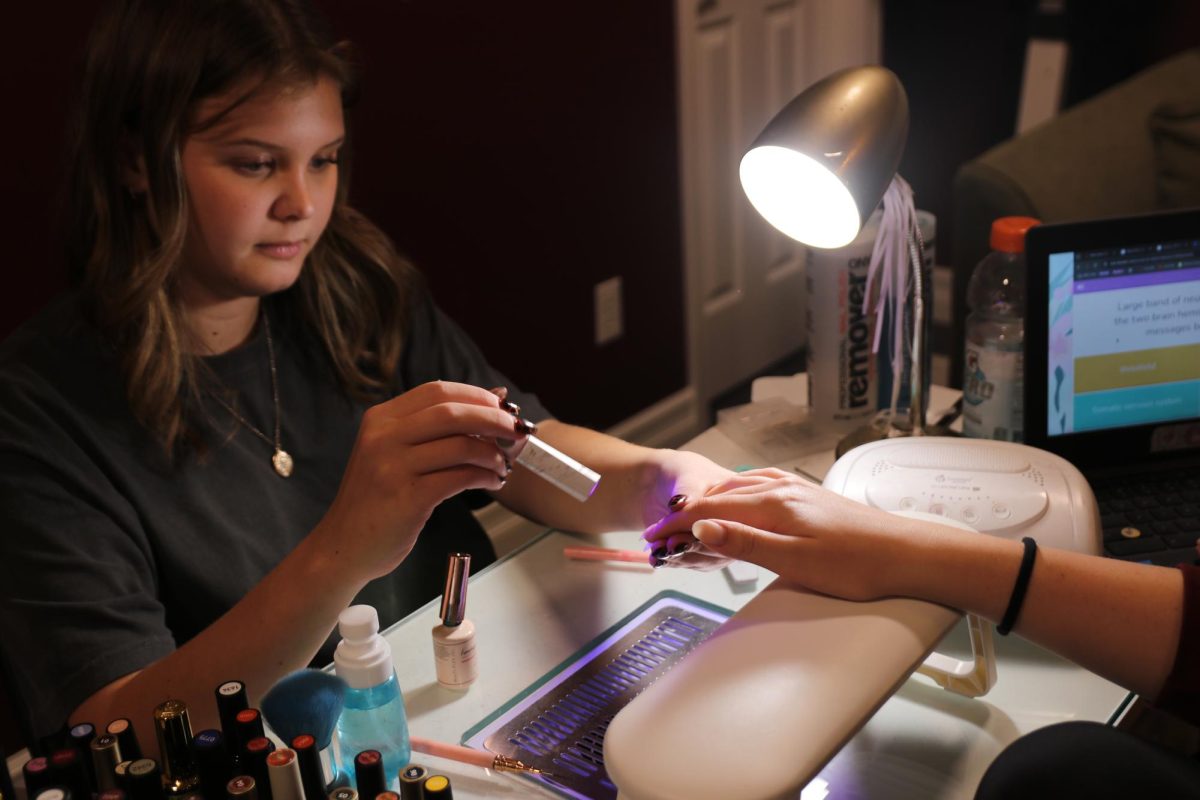 Jordan Farmer shines her UV light onto Audrey Saunders' recently gelled nails. 