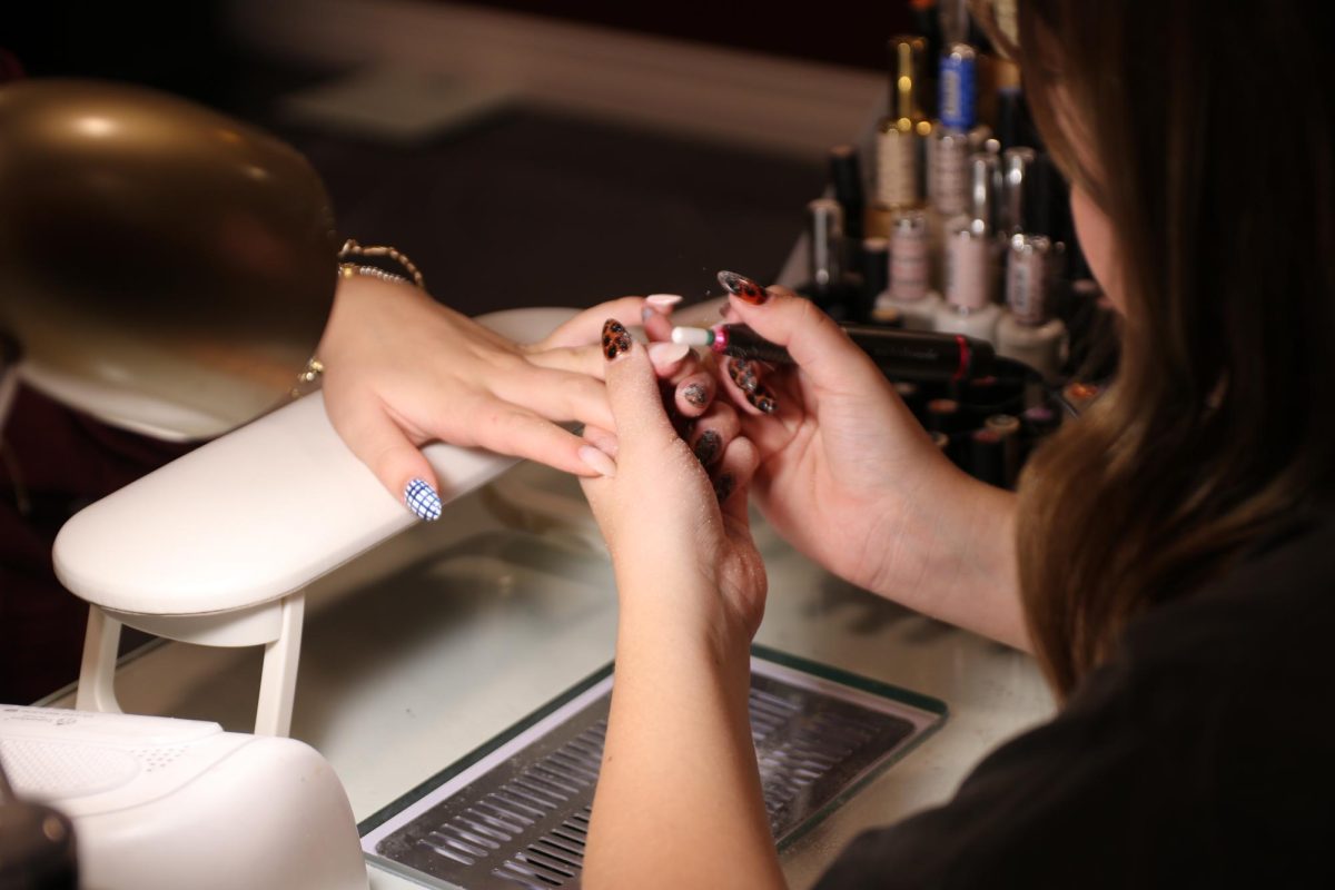Jordan Farmer, junior, "debulks" Audrey Saunders' original nails. This allows access to the nexts steps of the nail process.