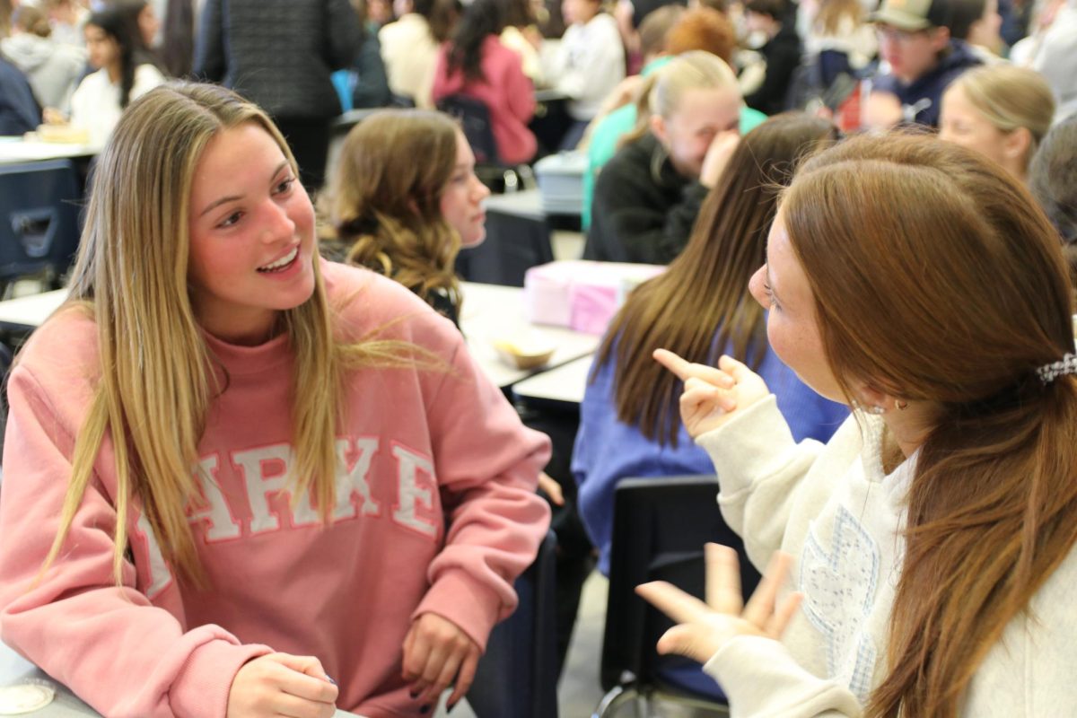 Juniors Kenzie Knodle and Marley Biggs talk with each other during lunch. Knodle is wearing a Parke sweatshirt, an article of clothing that's been trending recently. The brand started in July 2022 and has expanded from selling denim items to everyday wear in 2023, according to the Parke website.