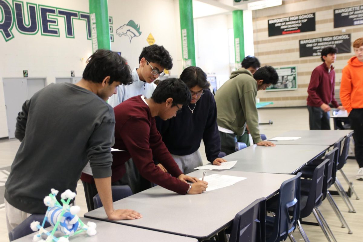 Sophomores Ashwin Premkumar, Eshaan Vaduka and Sree Charan Katabathuni answer questions on their lab sheet after the egg drop lab, calculating their performance score according to the score criteria. The egg drop competition relates to Unit 8 and 9 Springs and Momentum in AP Physics 1. 