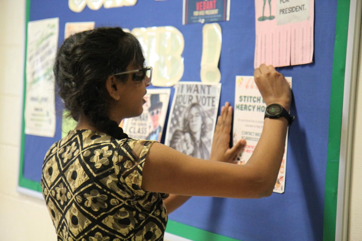 Junior Raghavi Garre, president of the Stitch Club, hangs posters for the clothing drive with Mercy Hospital being held over the summer.